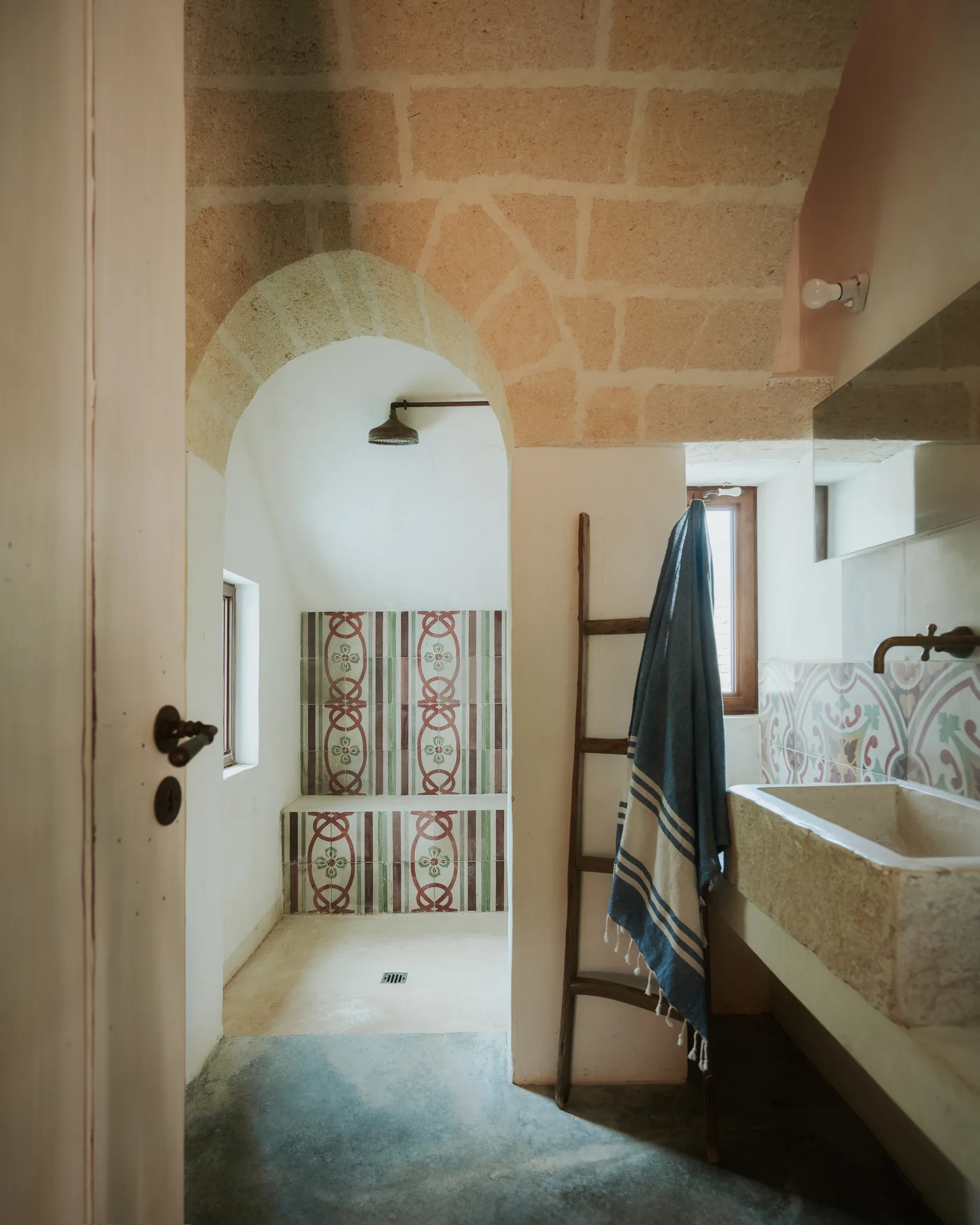 The bathroom: arched walk-in shower, patterned tiles and stone basin