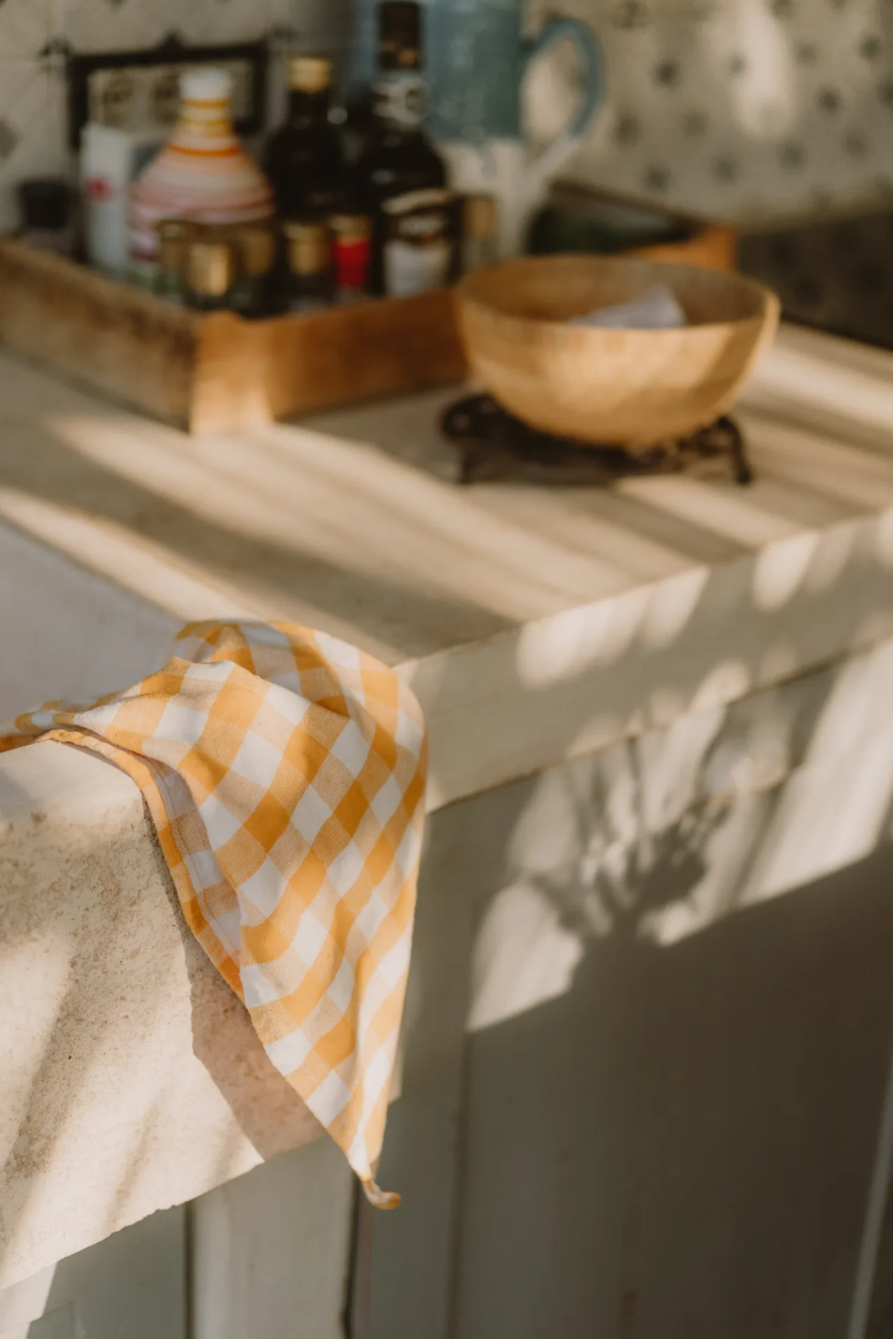A checked tea towel and kitchen things in the afternoon light