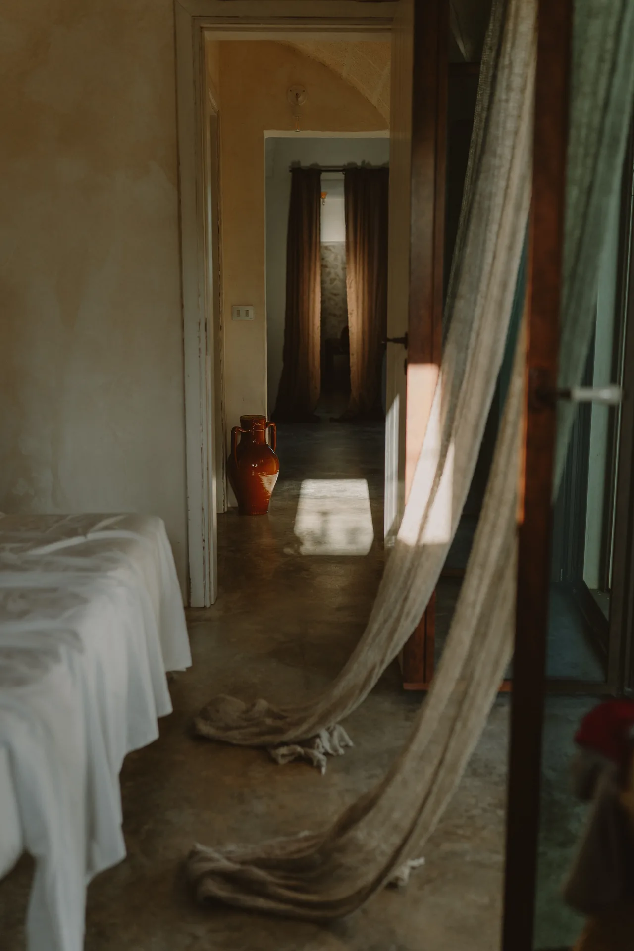 Afternoon light along the corridor, a linen curtain drawn aside