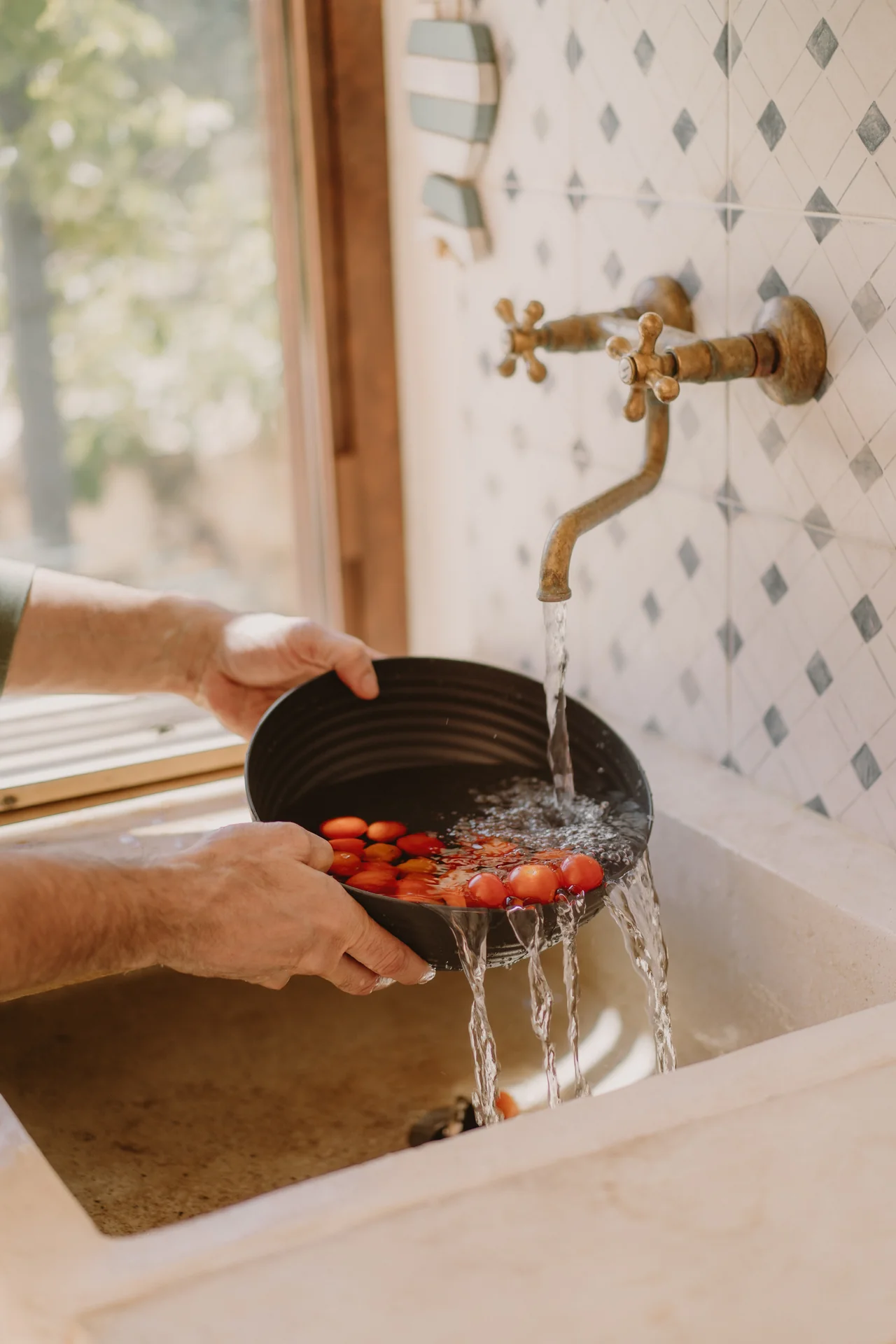 Cherry tomatoes rinsed under the brass tap over the old stone sink