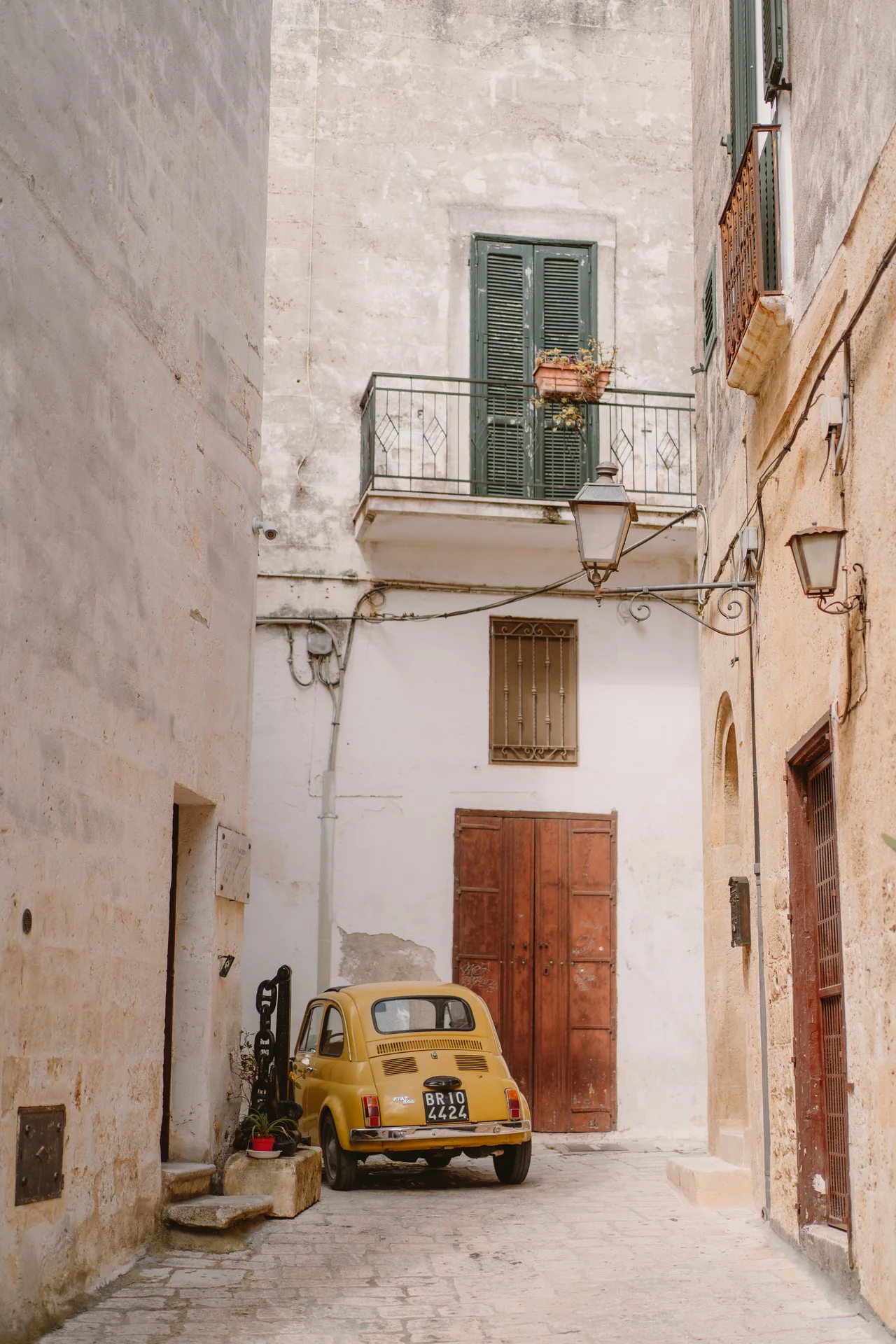 A yellow Fiat 500 among the stone houses of Maruggio