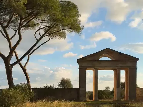 A classical stone gateway among pine trees, on a green lawn