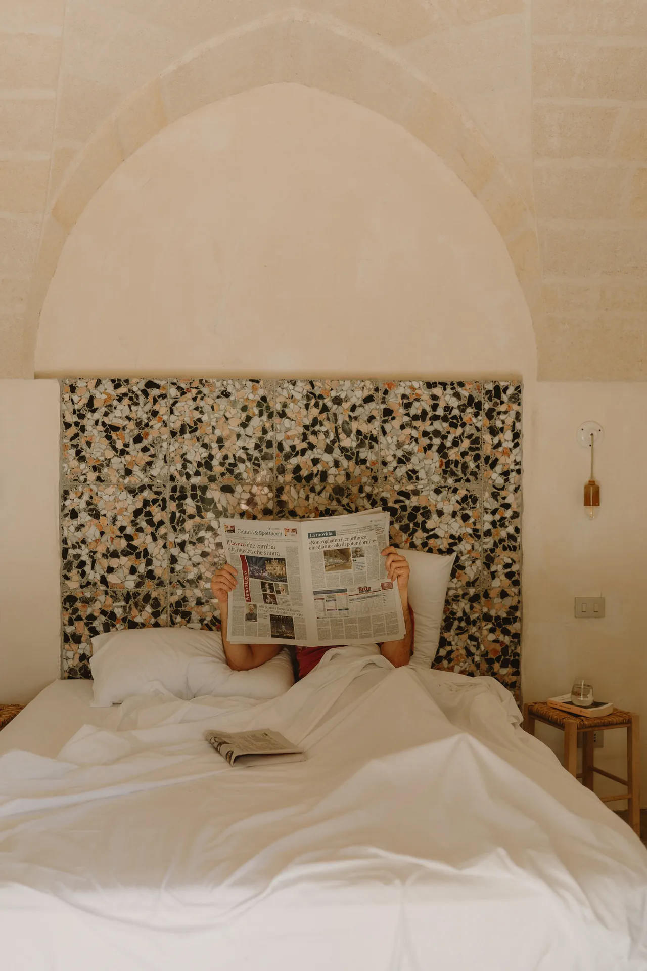 Reading the paper in bed, in the bedroom beneath the stone vault