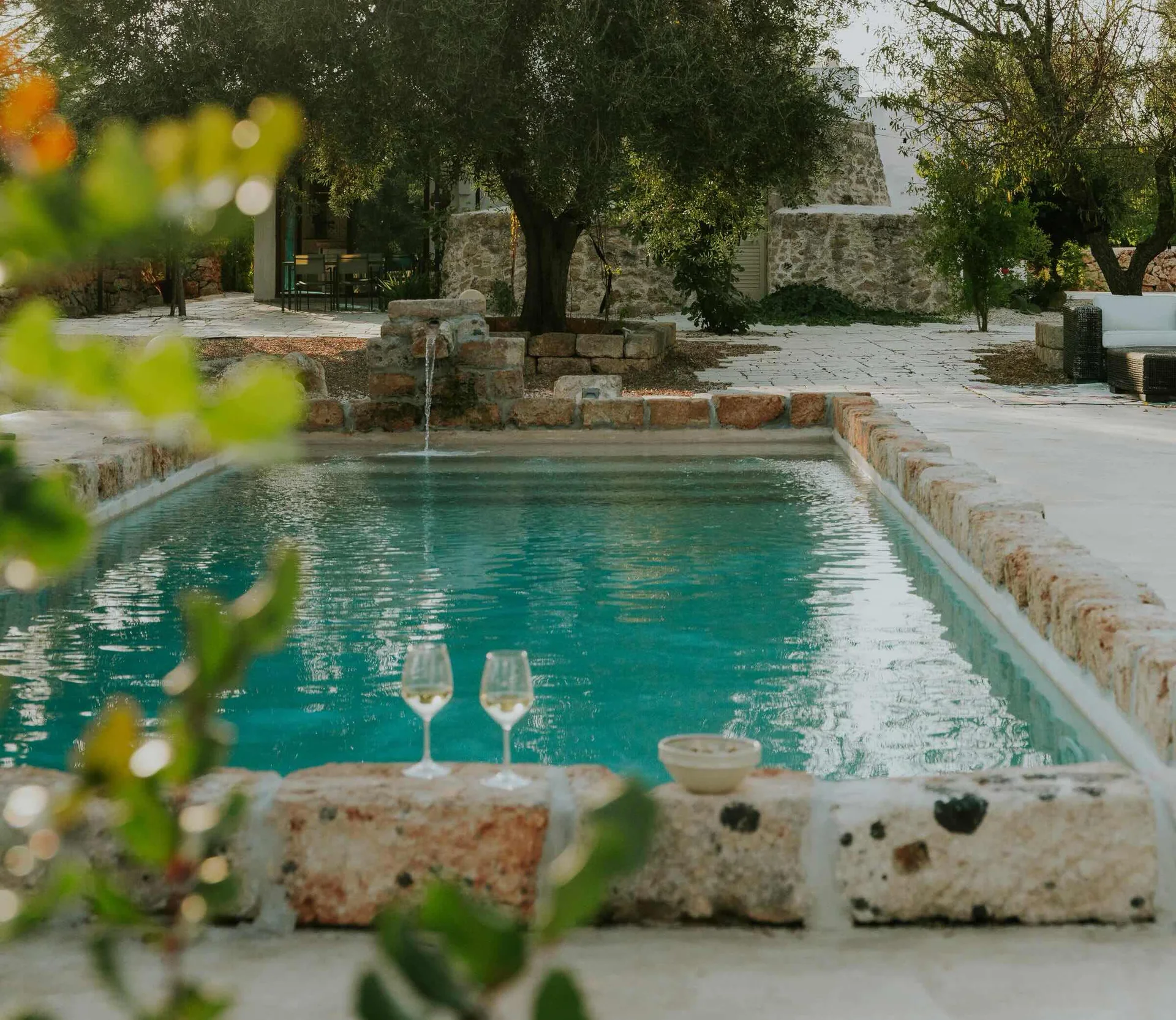 The private pool, stone house and two wine glasses by the water