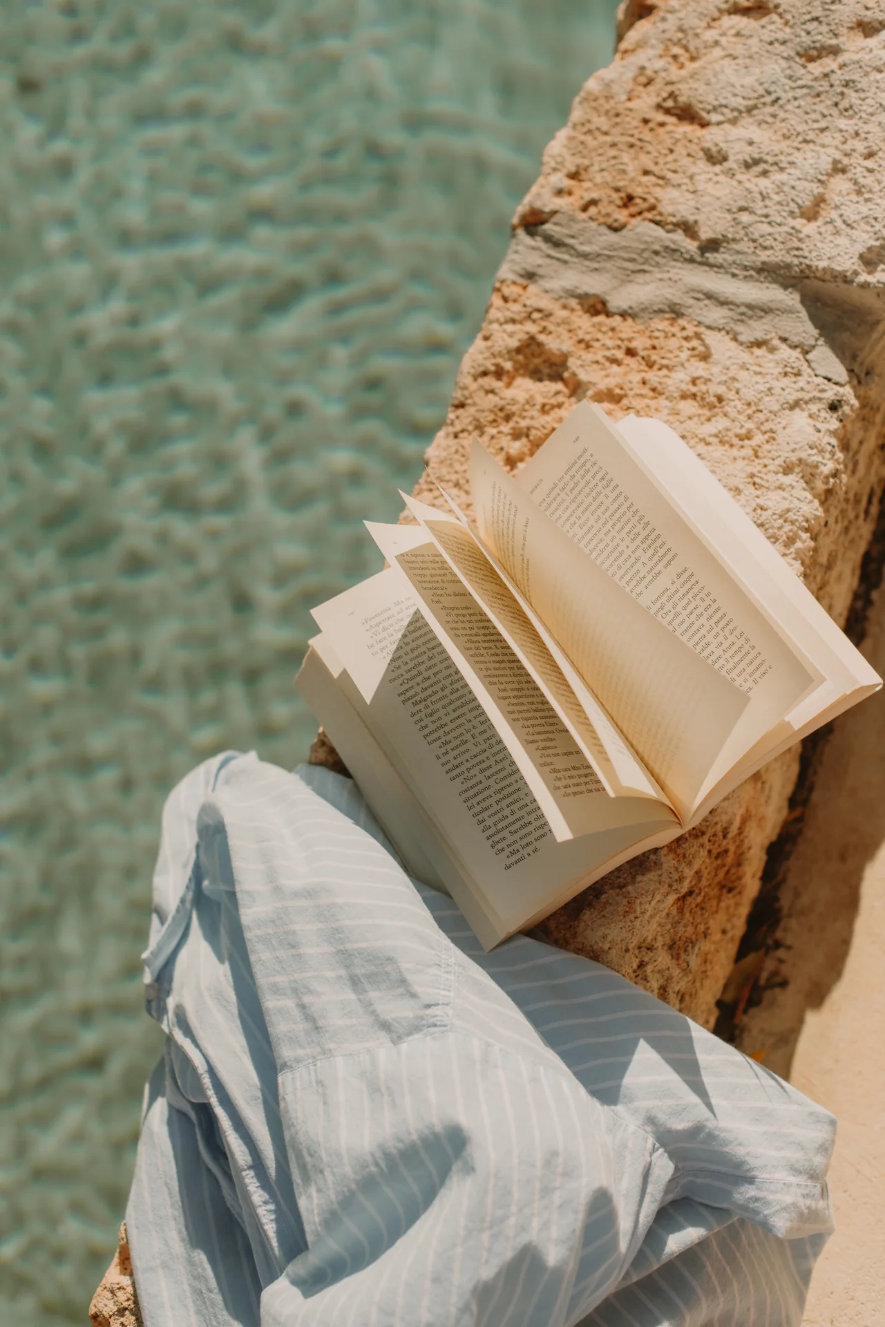 An open book and a linen towel beside the private pool