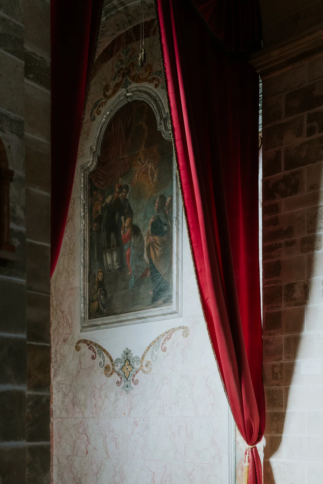 A fresco in Maruggio’s mother church, framed by red curtains
